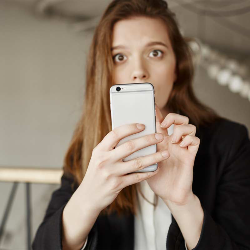 Femme au visage inquiet fixant l’écran de son téléphone